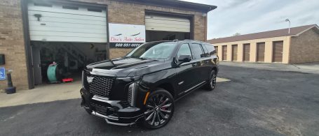 Luxury black SUV parked outside a garage with a neatly paved lot.